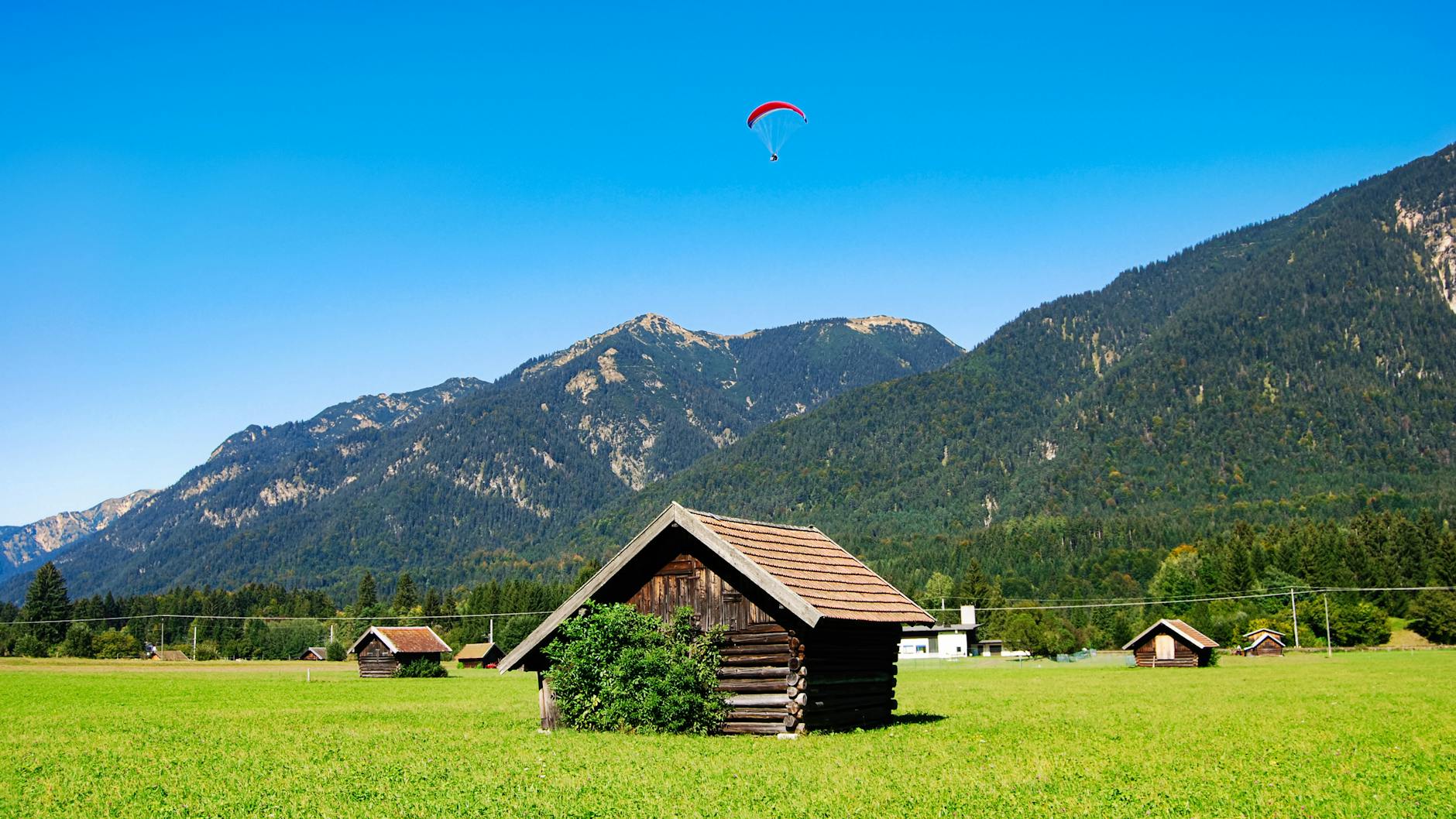 brown wooden house on grass field near mountain
